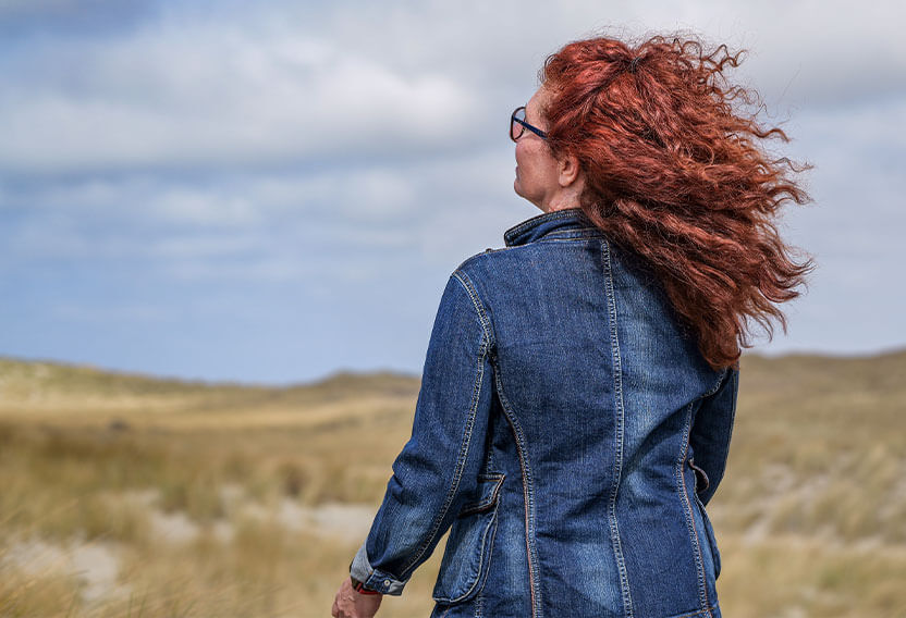 Silke auf einer Düne und in den Blick in die Ferne gerichtet